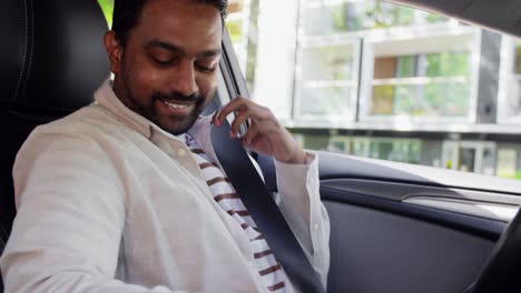 Smiling-Indian-Man-or-Driver-Driving-Car.transport,-safety-and-people-concept-happy-smiling-indian-man-or-driver-fastening-seat-belt-in-car