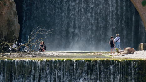 Young-people-playing-enjoying-the-water-in-front-of-big-waterfall-slow-motion