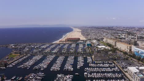 Descending-and-panning-aerial-shot-of-the-King-Harbor-Marina-in-Redondo-Beach-with-Hermosa-Beach-in-the-background-along-the-coast-in-Southern-California