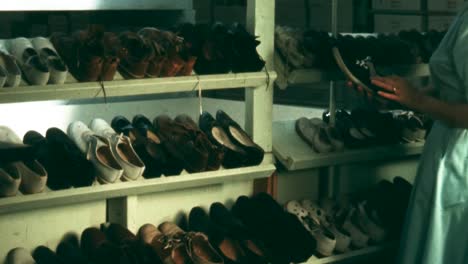 1960s-WOMAN-PUTS-PAIR-OF-SHOES-ON-RACK