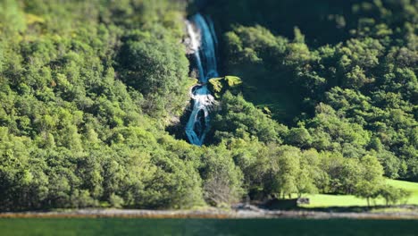 Ein-Tilt-Shift-Video-Fängt-Einen-Ruhigen-Wasserfall-An-Der-Küste-Des-Naeroy-Fjordwalds-Ein,-Umgeben-Von-Lebendigem-Grün