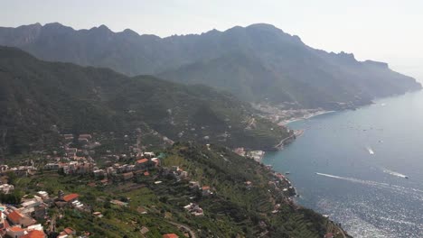 Ravello,-Amalfi-Coast,-Italy-Aerial-Drone-Footage-Panning-from-the-Mountains-to-reveal-the-Sea-with-Boats-Driving-in-the-Water