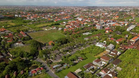 Canggu-Village-in-Badung-Regency,-Bali,-seen-from-above,-featuring-traditional-Balinese-homes,-vibrant-greenery,-and-a-vast-horizon