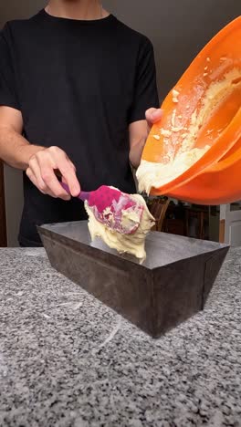 Vertical-shot-of-a-man-pouring-pudding-mix-into-a-metal-baking-pan