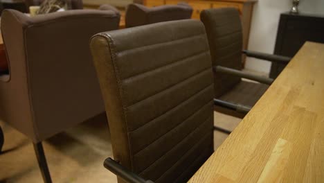 Close-up-of-Leather-armchairs-at-a-wooden-dining-table-inside-furniture-shop