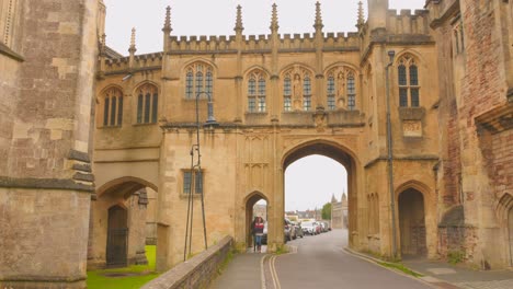 Two-Women-Walk-Through-Archway-Of-Chain-Gate-In-Wells,-Somerset,-UK