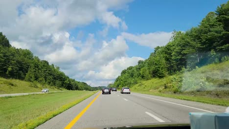 High-quality-footage-capturing-a-scenic-drive-through-a-highway-surrounded-by-lush-greenery-and-rolling-hills