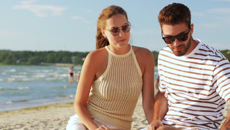 Glückliches-Paar-Mit-Essen-Beim-Picknick-Am-Strand.-Freizeit,-Beziehungen-Und-Menschen-Konzept-Glückliches-Paar-Mit-Essen,-Das-Trauben-Isst-Und-Am-Strand-Picknickt