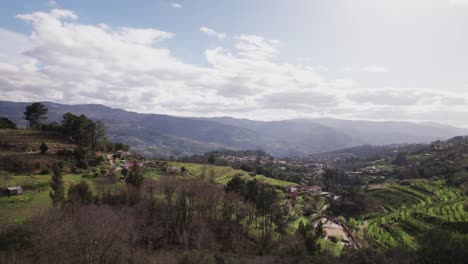 Paisaje-De-Granjas-En-Una-Zona-Rural-De-Portugal,-Con-Pequeñas-Montañas-Al-Fondo-Y-Un-Cielo-Nublado.