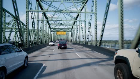 Wenn-Man-über-Eine-Autobahnbrücke-Fährt,-Entfaltet-Sich-Der-Blick-Auf-Den-Fluss-Darunter,-Die-Fahrenden-Fahrzeuge-Und-Die-Umgebende-Stadtlandschaft,-Alles-Unter-Einem-Weiten,-Offenen-Himmel