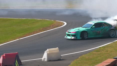 Green-car-drifting-tight-curves-with-lots-of-smoke-behind