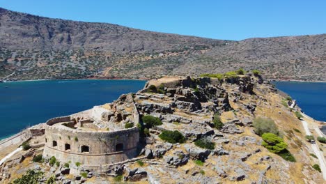 Órbita-Aérea-Sobre-El-Bastión-De-La-Fortaleza-Veneciana-De-Spinalonga-Y-Turistas-En-La-Cima,-Creta,-Grecia