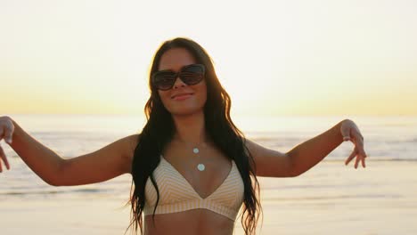 Happy-Woman-in-Bikini-Swimsuit-Dancing-on-Beach.people,-summer-and-swimwear-concept-happy-smiling-young-woman-in-bikini-swimsuit-dancing-on-beach