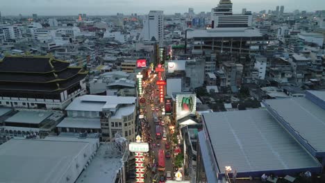 Drone-fly-busy-Chinatown-streets-of-Bangkok,-Thailand-at-early-nighttime,-illuminated-city