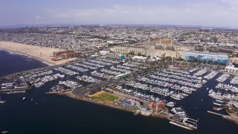 Wide-panning-aerial-shot-of-the-King-Harbor-Marina-with-Hermosa-Beach-visible-to-the-north-in-Redondo-Beach,-California