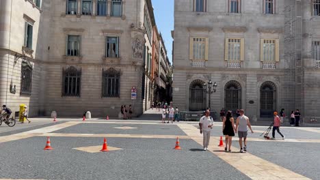 Menschen,-Die-über-Einen-Sonnigen-Platz-In-Barcelona-Mit-Historischen-Gebäuden-Im-Hintergrund-Spazieren