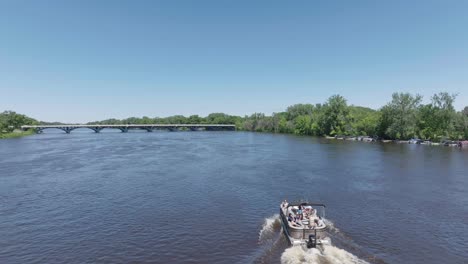 Drone-view-of-a-pontoon-carrying-tourists-through-Mississippi-river-in-Minnesota,-USA-on-a-bright-sunny-day