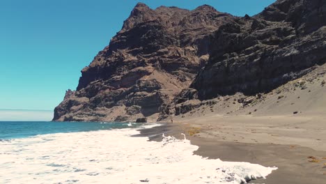 Idyllic-scene-of-a-woman-relaxing-unwinding-at-unspoiled-virgin-beach-in-Gran-Canaria,-Spain-during-summer-time-on-vacations