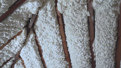 Panning-shot-of-an-attic-with-poorly-installed-foam-insulation