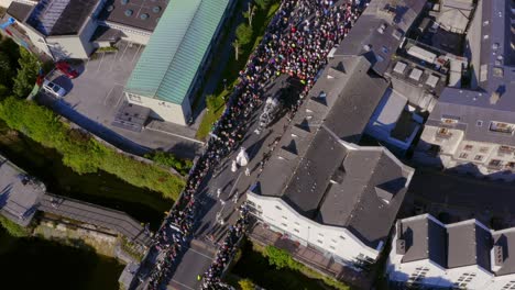 Vista-Aérea-Desde-Arriba-Del-Desfile-Del-Festival-Internacional-De-Las-Artes-De-Galway-Con-Multitudes-Siguiéndolo-A-Medida-Que-Se-Acerca-Al-Río-Corrib