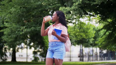 Student-Girl-Reading-Book-and-Drinking-Coffee.education,-school-and-people-concept-happy-smiling-african-american-student-girl-reading-book-and-drinking-takeaway-coffee-in-city