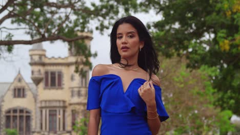 Amidst-a-sunny-park,-a-girl-in-a-blue-dress-stands-with-castles-in-the-background