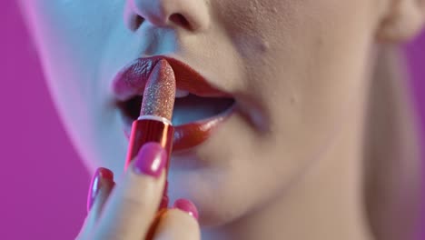 Facial-Makeup,-Close-Up-Of-Woman's-Mouth-Applying-Red-Lipstick-To-Her-Lips-Against-Purple-Background