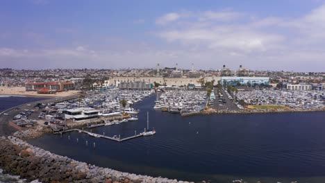 Aerial-low-panning-shot-of-the-breakwater-around-the-bay-at-the-King-Harbor-Marina-in-Redondo-Beach,-California