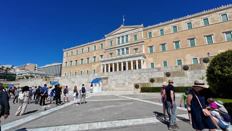 POV-shot-of-Monument-to-the-Unknown-Soldier-on-a-sunny-day-with-visitors-exploring-it-in-Athens,-Greece