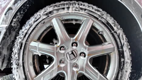 Closeup-of-Honda-logo-on-a-silver-car-wheel-with-its-tire-being-washed-with-foam