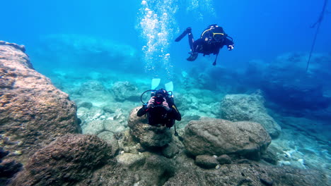 Vista-Frontal-De-Buceadores-Con-Traje-De-Neopreno-Y-Tubo-De-Oxígeno-En-La-Parte-Posterior-Disfrutando-Del-Snorkeling-Bajo-El-Mar-En-Grecia