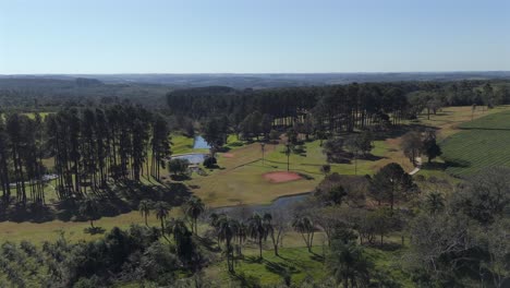 Middle-altitude-and-approaching-aerial-movement-about-the-local-golf-club-and-green-tea-fields,-Argentina