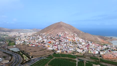 Aerial-view-of-Galdar-town-city-village-under-the-mountain-against-seascape-in-Gran-Canaria,-Spain