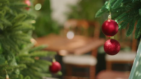 Bolas-Rojas,-Globos,-Colgando-De-Un-árbol-De-Navidad-Dentro-De-Un-Estante-De-La-Casa-Moderna,-Se-Centran-En-La-Mesa-Y-La-Silla-De-Madera-Listas-Para-La-Celebración-De-La-Fiesta.