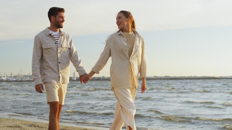 Happy-Couple-Walking-Along-Summer-Beach.summer-holidays-and-people-concept-happy-couple-walking-along-beach-in-tallinn,-estonia