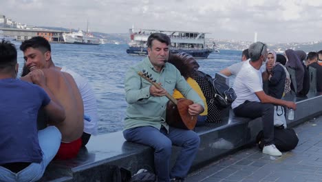 Ein-Türkischer-Mann-Spielt-Eine-Laute-Als-Straßenmusikant-Auf-Dem-Hafenpier-In-Istanbul