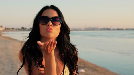 Woman-Taking-Selfie-and-Blowing-Kiss-on-Beach.people,-summer-and-swimwear-concept-happy-smiling-young-woman-in-bikini-swimsuit-taking-selfie-and-blowing-kiss-on-beach