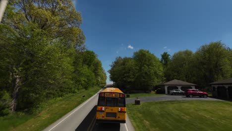 Aerial-FPV-tracking-shot-of-a-yellow-American-school-bus-on-a-rural-road-in-USA