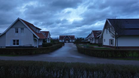 Crane-up-shot-of-an-empty-residential-suburb-with-houses,-village,-and-gardens-in-twilight