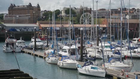 footage-of-Scarborough-Harbour,-North-Yorkshire-on-a-summer-day-the-harbor-has-boats-and-people-walking-around