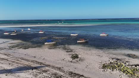 Boote-Vor-Anker-In-Der-Nähe-Des-Strandes,-Sanft-Wiegend-In-Den-Ruhigen-Gewässern-Von-Sansibar,-Tansania,-Dolly-In-Getan-Luftaufnahme