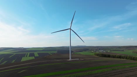 Windturbine-Steht-Hoch-Auf-Einem-Riesigen-Grünen-Feld-Unter-Einem-Klaren-Blauen-Himmel