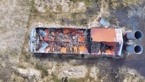 Drone-video-captures-an-abandoned-Iceland-farm,-surrounded-by-rocks-and-grasslands,-with-a-lake-in-the-distance,-showcasing-nature's-resilience-and-reclamation