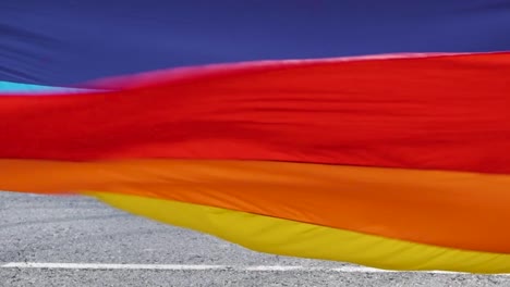 Big-pride-flag-being-carried-by-a-group-of-people,-symbolising-unity-and-support