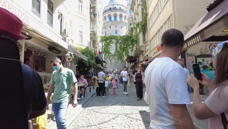 Busy-and-crowded-pedestrian-area-with-people-and-street-musicians-in-front-of-the-Galata-Tower,-Istanbul,-Turkey