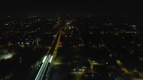 Aerial-drone-view-of-a-vibrant-cityscape-of-Chicago-at-night,-illuminated-by-the-dazzling-bursts-of-fireworks-along-a-bustling-main-street