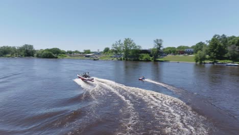 Rotating-aerial-view-of-a-boat-pulling-tubers-on-Mississippi-river-during-summer-morning-in-Minnesota,-USA