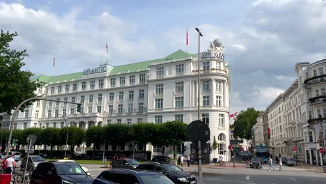 Escena-De-Tráfico-A-Lo-Largo-Del-Lago-Alster-En-Hamburgo-Con-El-Famoso-Hotel-Atlantic-Al-Fondo