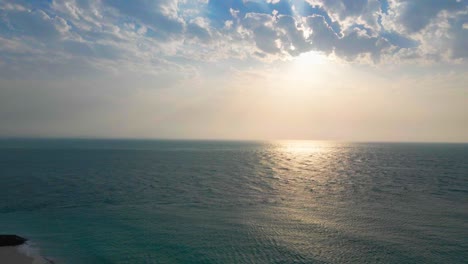 Luftaufnahmen-Einer-Drohne,-Die-Die-Heitere-Schönheit-Eines-Sonnenaufgangs-über-Einem-Ruhigen-Meer-Und-Einem-Leeren-Strand-Einfangen