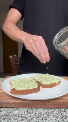 Adding-toasted-sesame-seeds-on-top-of-an-avocado-toast